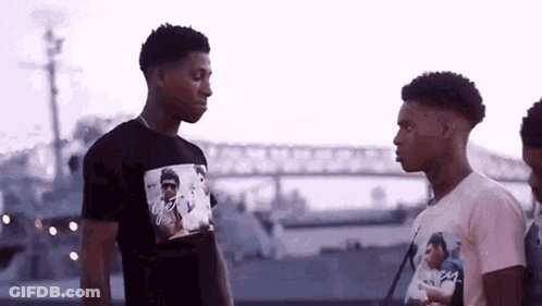 A Group Of Young Men Are Standing Next To Each Other In Front Of A Boat . GIF