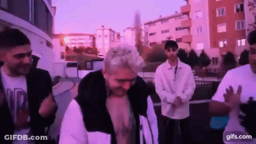 A Group Of Young Men Are Standing Next To Each Other On A City Street . GIF