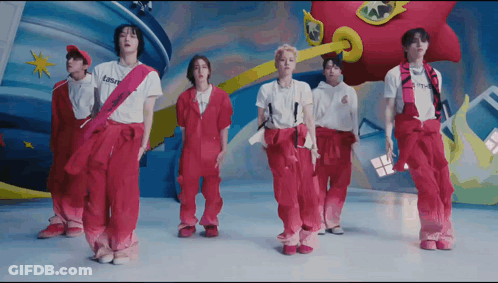 A Group Of Young Men Are Standing Next To Each Other Wearing Pink Overalls And White Shirts . GIF