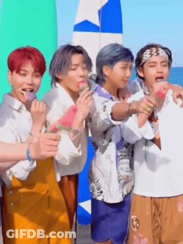 A Group Of Young Men Are Standing On A Beach Eating Watermelons . GIF