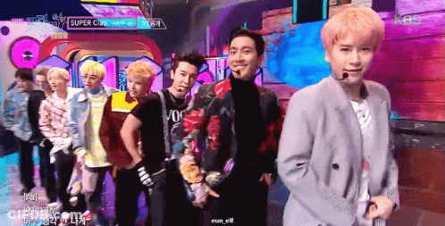A Group Of Young Men Are Standing On A Stage With A Sign That Says Super Cup GIF