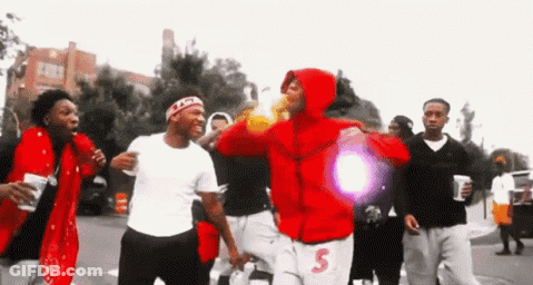 A Group Of Young Men Are Walking Down A Street . GIF
