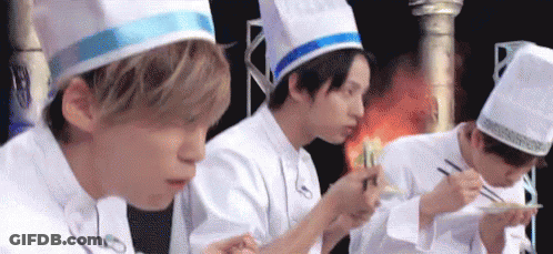 A Group Of Young Men In Chef Hats Are Eating Food With Chopsticks . GIF