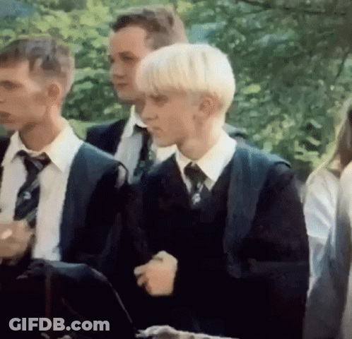 A Group Of Young Men In Suits And Ties Are Standing Next To Each Other In A Park . GIF