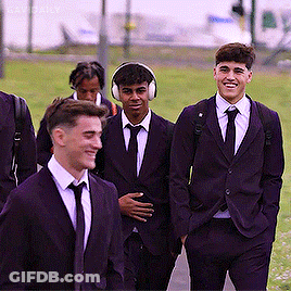 A Group Of Young Men In Suits And Ties Are Walking Together GIF