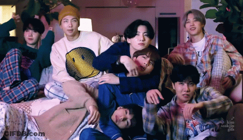 A Group Of Young Men Posing For A Picture With One Wearing A Smiley Face Sweatshirt GIF