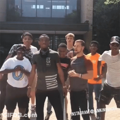 A Group Of Young Men Standing In Front Of A Building With One Man Wearing A Shirt That Says Ov Sn On It GIF