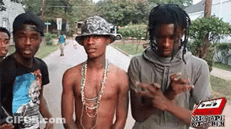 A Group Of Young Men Standing Next To Each Other On A Street . GIF