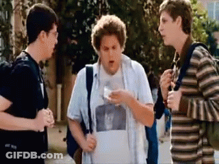 A Group Of Young Men Standing On A Sidewalk Talking To Each Other GIF