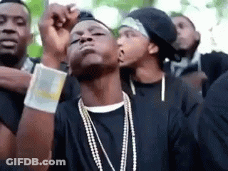 A Group Of Young Men Wearing Black Shirts And Pearl Necklaces Are Standing Next To Each Other . GIF