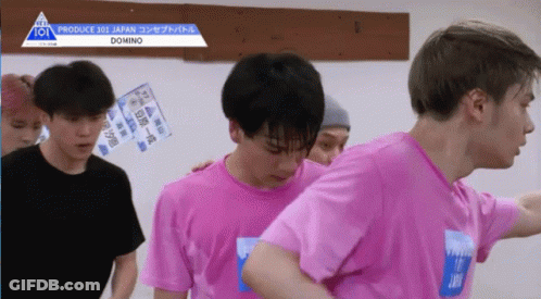 A Group Of Young Men Wearing Pink Shirts Are Standing In Front Of A Sign That Says Produce 101 Japan GIF