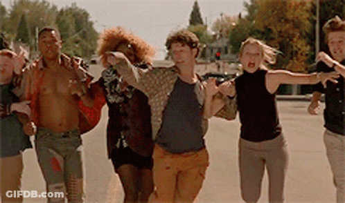 A Group Of Young People Are Running Down A Street GIF