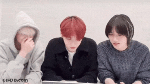 A Group Of Young People Are Sitting Around A Table Looking At A Laptop . GIF
