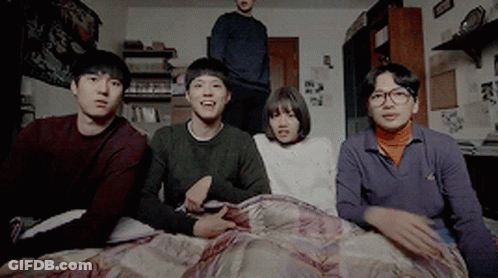 A Group Of Young People Are Sitting On A Bed Looking At Something GIF
