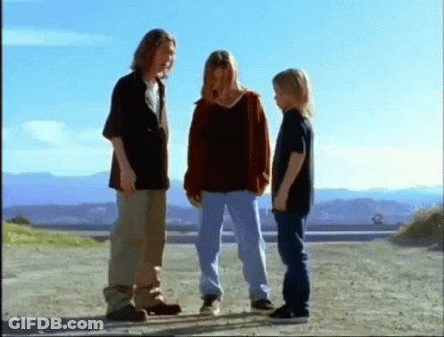 A Group Of Young People Are Standing On A Dirt Road . GIF
