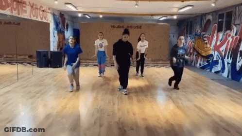 A Group Of Young Women Are Dancing In A Dance Studio With Graffiti On The Wall . GIF