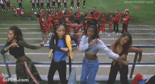 A Group Of Young Women Are Dancing In A Stadium While Cheerleaders Are Standing In The Background . GIF