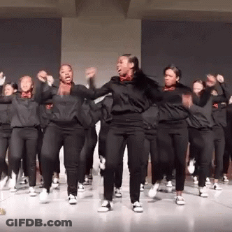 A Group Of Young Women Are Dancing Together On A Stage In A Room . GIF