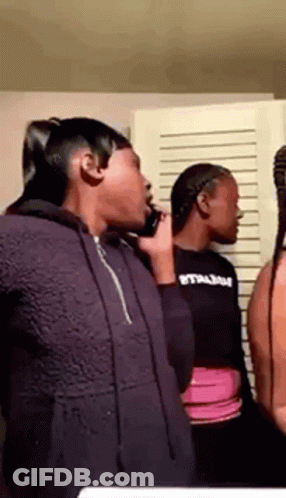 A Group Of Young Women Are Standing Next To Each Other In A Room Talking On Cell Phones . GIF