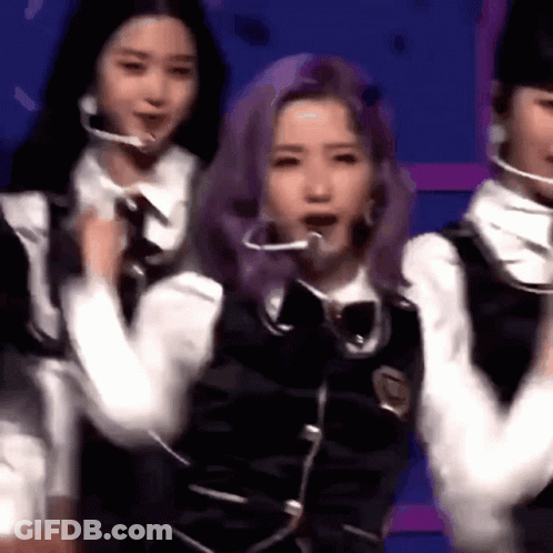 A Group Of Young Women Are Standing Next To Each Other On A Stage . One Of The Girls Has Purple Hair . GIF
