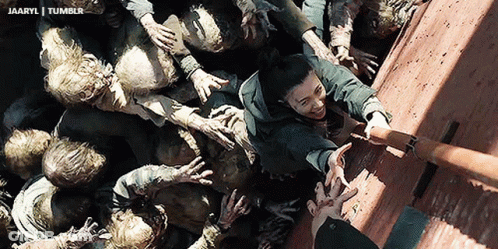 A Group Of Zombies Are Reaching For A Man 'S Hand In A Scene From A Movie GIF