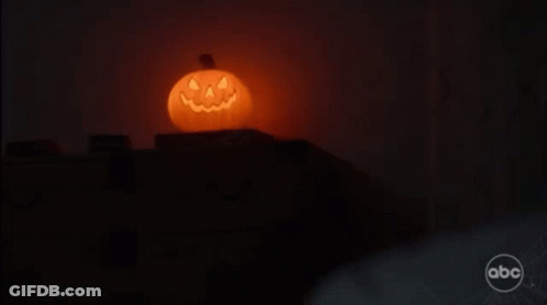 A Halloween Pumpkin With A Face Carved Into It Is Lit Up In The Dark . GIF