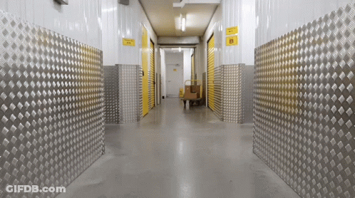 A Hallway With Metal Walls And A Yellow Sign That Says ' Warehouse ' On It GIF