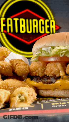 A Hamburger And Fried Shrimp Are On A Plate In Front Of A Sign That Says Fatburger GIF