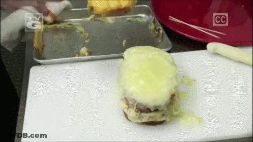 A Hamburger Is Sitting On A White Cutting Board With A Cc Logo On It GIF