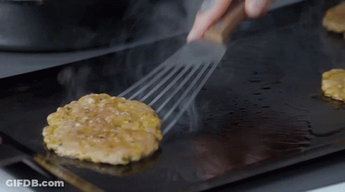 A Hamburger Patty Is Being Cooked On A Grill GIF