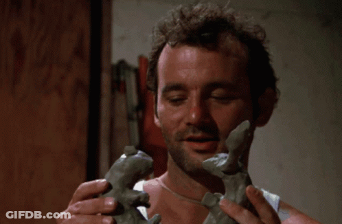 A Hand Holds A Piece Of Clay In Front Of A Pile Of Granite GIF