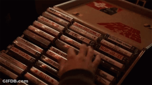 A Hand Is Holding A Cassette Tape That Says Rush On It GIF