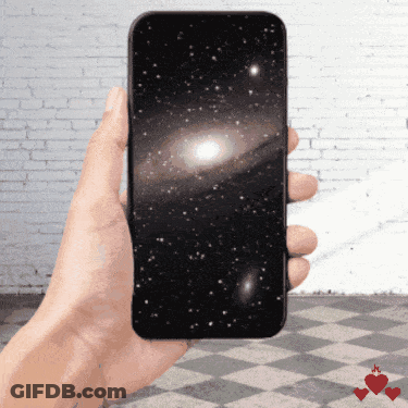 A Hand Is Holding A Cell Phone With A Picture Of The Galaxy On The Screen GIF