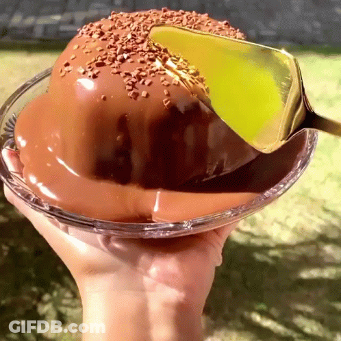 A Hand Is Holding A Glass Bowl Of Chocolate Cake GIF