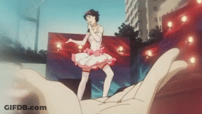 A Hand Is Holding A Picture Of A Girl In A Tutu Singing Into A Microphone . GIF