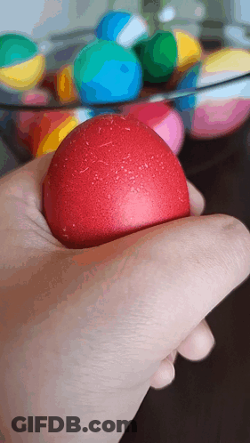 A Hand Is Holding A Red Ball In Front Of A Bowl Of Balls GIF