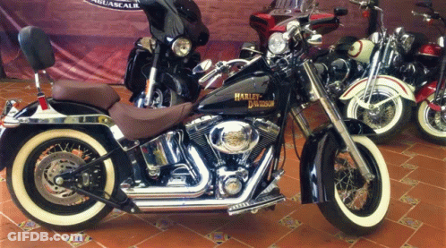 A Harley Davidson Motorcycle Is Parked In Front Of A Sign GIF
