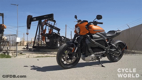 A Harley Davidson Motorcycle Is Parked On The Side Of The Road In Front Of An Oil Pump GIF