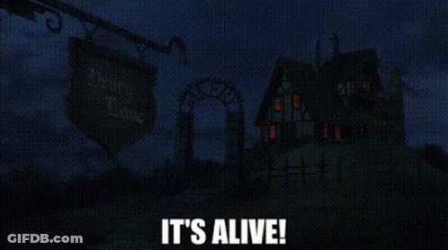 A Haunted House Is Lit Up At Night With The Words `` It 'S Alive '' Written In White Letters . GIF