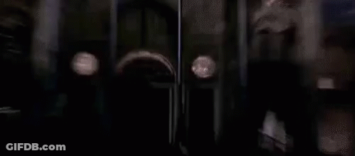 A Haunted Mansion Sign Is Behind A Fence In The Rain . GIF