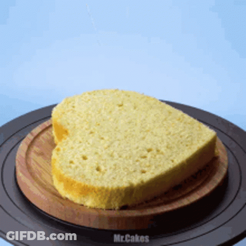 A Heart Shaped Loaf Of Bread Is On A Wooden Cutting Board GIF