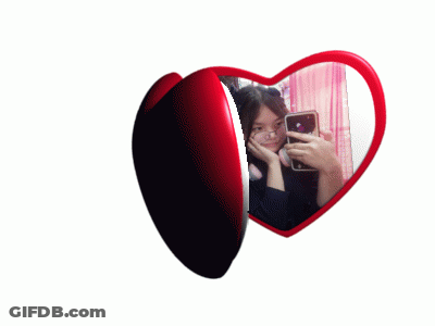 A Heart Shaped Mirror Shows A Woman Taking A Selfie GIF