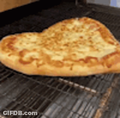 A Heart Shaped Pizza Is Sitting On A Wire Rack On A Grill . GIF