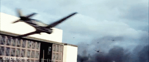 A Helicopter Is Flying Over A Building With Smoke Coming Out Of The Window GIF
