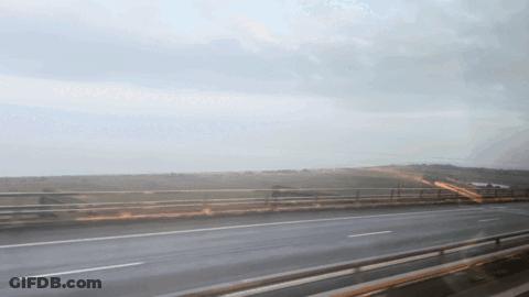 A Highway With A Bridge In The Background And A Cloudy Sky GIF