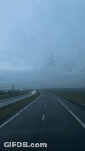 A Highway With A Few Cars On It And A Cloudy Sky GIF