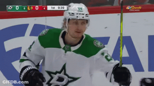 A Hockey Player In A Green And White Jersey Is Standing On The Ice GIF
