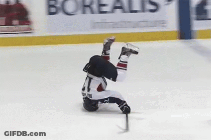 A Hockey Player Is Falling On His Back On The Ice While Holding A Puck . GIF