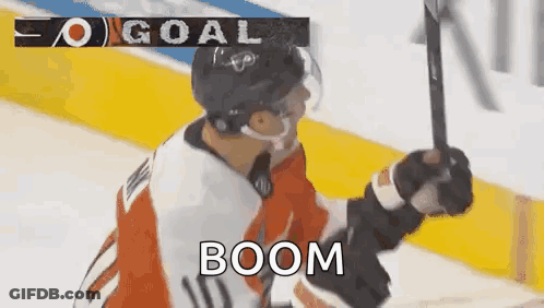 A Hockey Player Is Holding A Hockey Stick In The Air While Celebrating A Goal . GIF