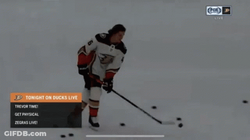 A Hockey Player Is Skating In The Snow With A Puck And A Stick . GIF
